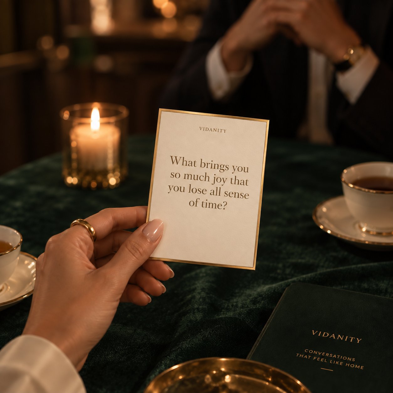 A hand holding a VIDANITY question card at a candlelit table
